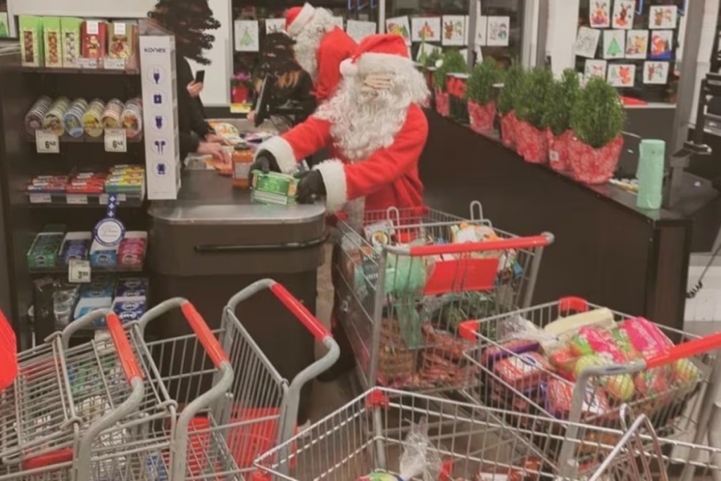 Une personne déguisée en Père Noël à la caisse avec 2 paniers d'épicerie très remplis